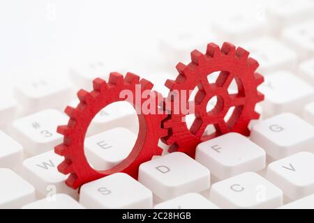 Two red gears on computer keyboard Stock Photo