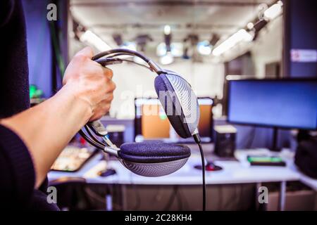 Studio recording: Young is holding headphones in the recording studio, studio in the blurry background Stock Photo