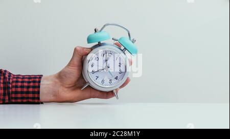 Retro styled white alarm clock in man’s hand, isolated Stock Photo