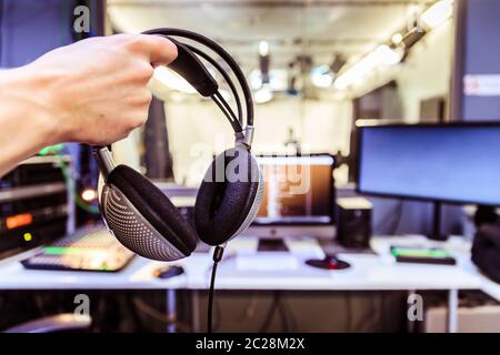 Studio recording: Young is holding headphones in the recording studio, studio in the blurry background Stock Photo