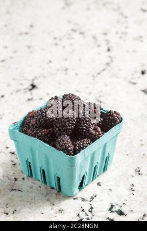 Fresh and ripe blackberries from the farmers market in blue paper box on marble background Stock Photo