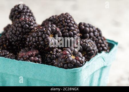 Fresh and ripe blackberries from the farmers market in blue paper box, closeup Stock Photo