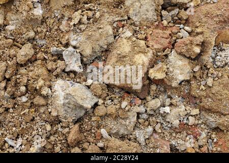 Rough broken concrete and brick, mixed with soil and stones from an excavation - abstract background texture Stock Photo