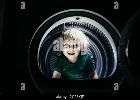 Happy child, sitting in thumble dryer, smiling happily Stock Photo