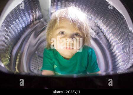 Happy child, sitting in thumble dryer, smiling happily Stock Photo