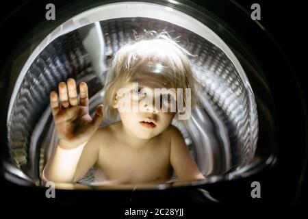 Happy child, sitting in thumble dryer, smiling happily Stock Photo