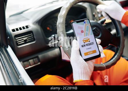 Delivery man sitting in car getting new work request on his smart phone, horizontal close-up shot Stock Photo