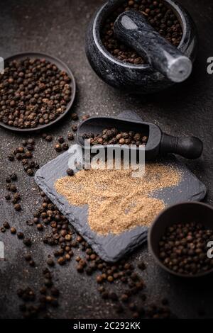 Black pepper corns and black pepper powder on dark background Stock Photo