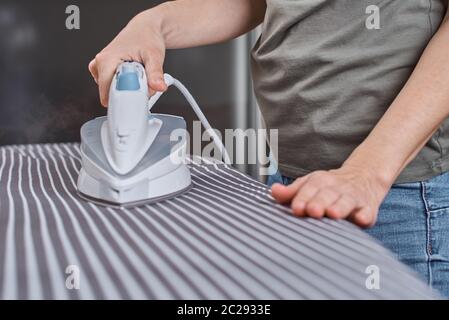 Woman ironing clothes on ironing board with modern iron Stock Photo