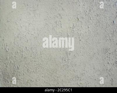 Grey paint peeling on a metallic surface background. Old grungy, weathered painted wall texture. Cracked, dirty, silver plaster falling off the constr Stock Photo