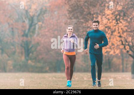 Couple in wonderful fall landscape running for better fitness towards the camera Stock Photo