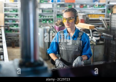 Woman worker operating a machine tool in metal workshop or factory in a diligent manner Stock Photo