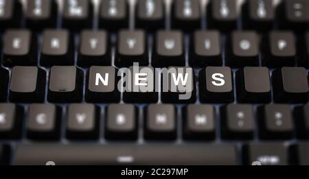 Online news, journalism concept. News word written on keypad. Black keys with white letters message for press articles on pc keyboard. Blur buttons ba Stock Photo