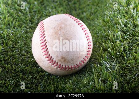 Old Baseball in closeup over synthetic grass, horizontal image Stock Photo