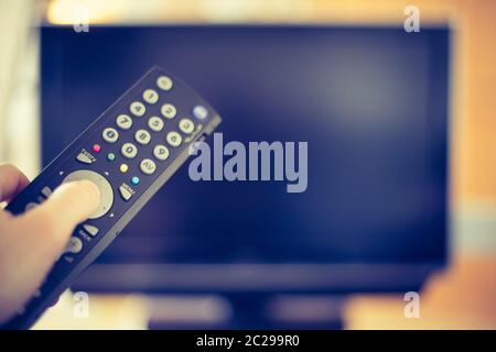 Male hand is holding TV remote control, smart TV. Stock Photo