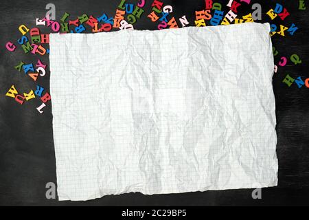 crumpled piece of paper from a school notebook in a cage on a black background, concept back to school Stock Photo