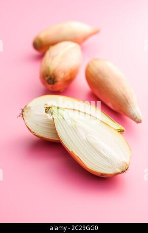 The golden shallot onion. Halved fresh bulbs on pink background. Stock Photo