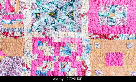 textile background - square pattern of patchwork scarf stitched from various silk strips and crushed pink cotton fabric Stock Photo