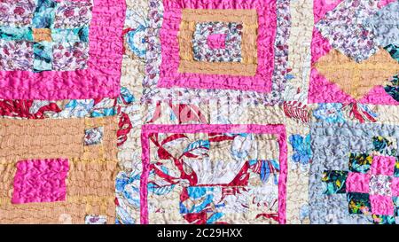 textile background - geometric ornament of patchwork scarf stitched from various silk strips and crushed pink cotton fabric Stock Photo