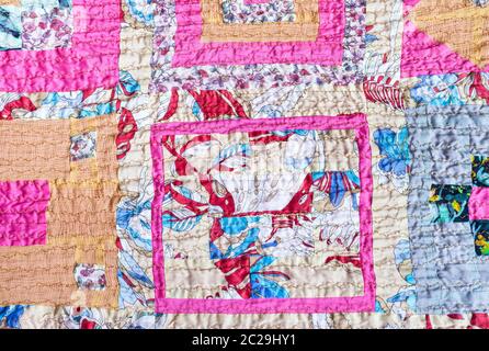 textile background - ornamental patchwork scarf stitched from various silk strips and crushed pink cotton fabric Stock Photo