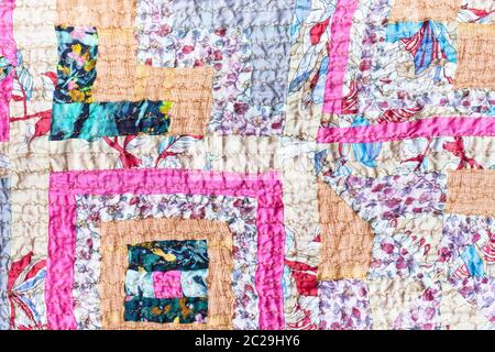 textile background - surface of patchwork scarf stitched from various silk strips and crushed pink cotton fabric Stock Photo