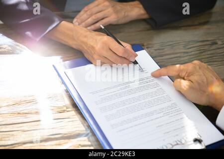 Close-up Of A Real Estate Agent Helping Client In Filling Contract Form Stock Photo