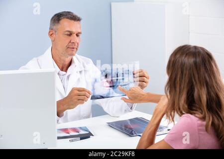 Mature Doctor Showing Dental X-ray To Patient In Hospital Stock Photo