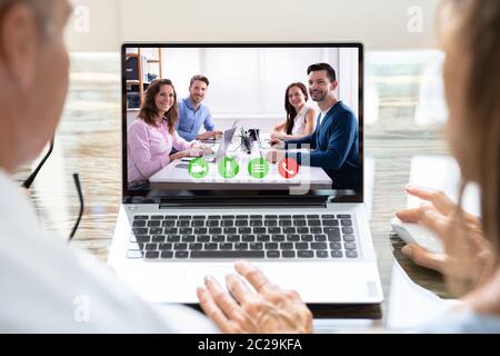 Two Businesspeople Video Conferencing With Smiling Male And Female Colleagues On Laptop Stock Photo