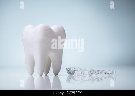White Ceramic Tooth Model And Transparent Mouth Guard Over Reflective Desk Stock Photo