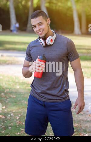 Portrait format runner smiling young latin man running jogging sports training fitness workout outdoor Stock Photo