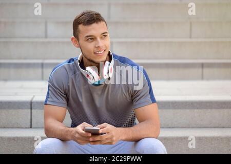 Smartphone cell phone listening to music young latin man looking up listen outdoor Stock Photo
