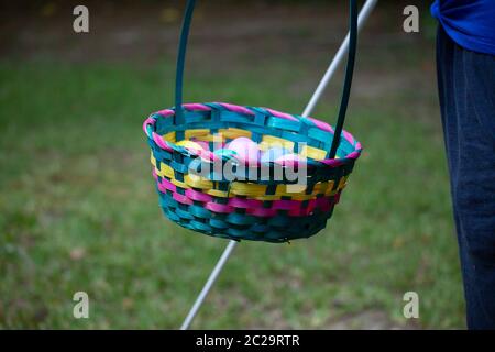 Blind woman carrying a cane and a colorful Easter basket filled with yellow, blue, green, purple, and pink eggs Stock Photo