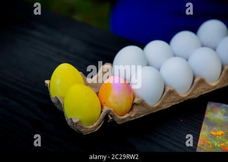 Close up of a dozen plastic Easter eggs in a carton with two eggs dyed yellow and one dyed pink and yellow Stock Photo