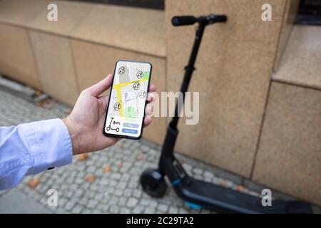 Young Man Using App To Rent Electric Scooter Stock Photo