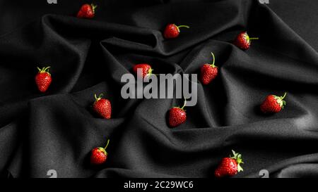 Strawberries on black fabric background. Beautiful combination of red and black High quality photo Stock Photo