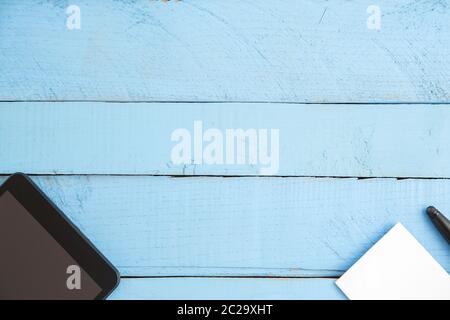 black tablet ,small notebook and black pen on blue wooden background. the view from the top Stock Photo