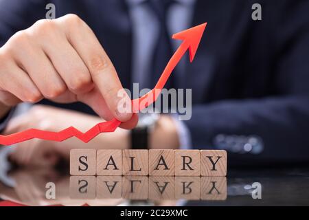 Person's Hand Holding Growth Arrow Near Salary Word Stock Photo