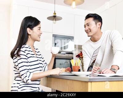 young asian couple working from home sitting kitchen counter having a discussion Stock Photo