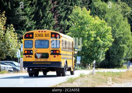 a yellow american school bus drives on the street Stock Photo