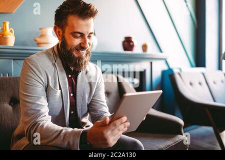 Young handsome businessman holding tablet working, relaxing Stock Photo