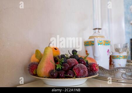 A fancy plate, bowl filled with plastic fake fruit. At Rundāle Palace in Pilsrundāle, Latvia. Stock Photo