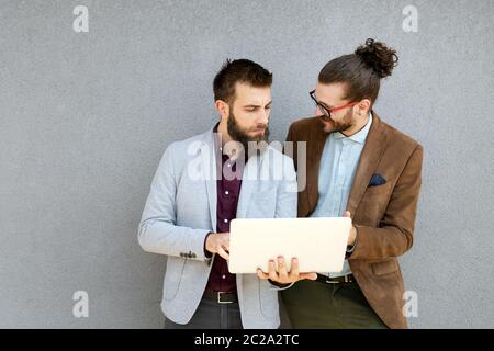 Positive successful business specialists discussing plan with laptop outdoors. Stock Photo