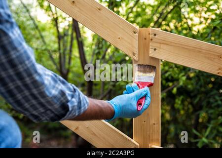 Adult craftsman carpenter with the brush painting the boards of a wooden fence. Housework, do it yourself. Stock Photography. Stock Photo