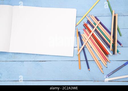 colored pencils and an album with space for text on a blue wooden background. the view from the top Stock Photo