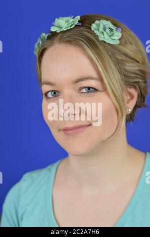 young blond woman with updo hair and cyan flowers Stock Photo