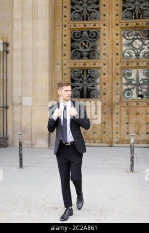 Handsome young man going near wooden door. Stock Photo