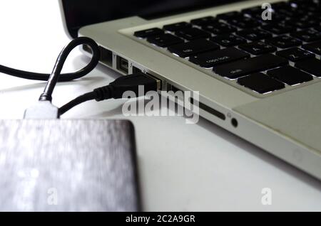 External hard drive connect to laptop computer on the white background. Stock Photo