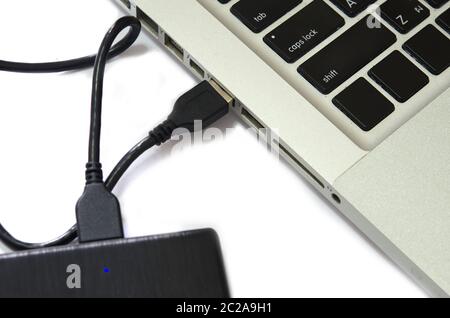 External hard drive connect to laptop computer on the white background. Stock Photo