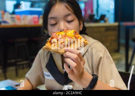 Beautiful Asian boy eating pizza in the restaurant. Stock Photo