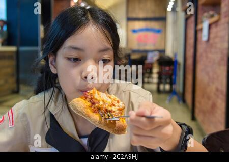 Beautiful Asian boy eating pizza in the restaurant. Stock Photo